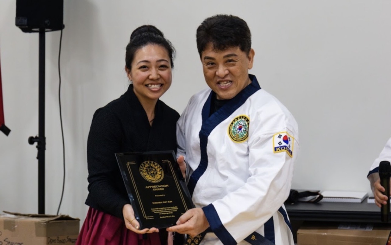 Grandmaster Moon K. Kim presenting an appreciation award to Master Amy Kim
